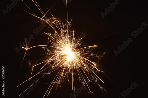 Christmas and New Year s illumination. Burning sparklers scatter bright exploding strips of sparks on a dark background.