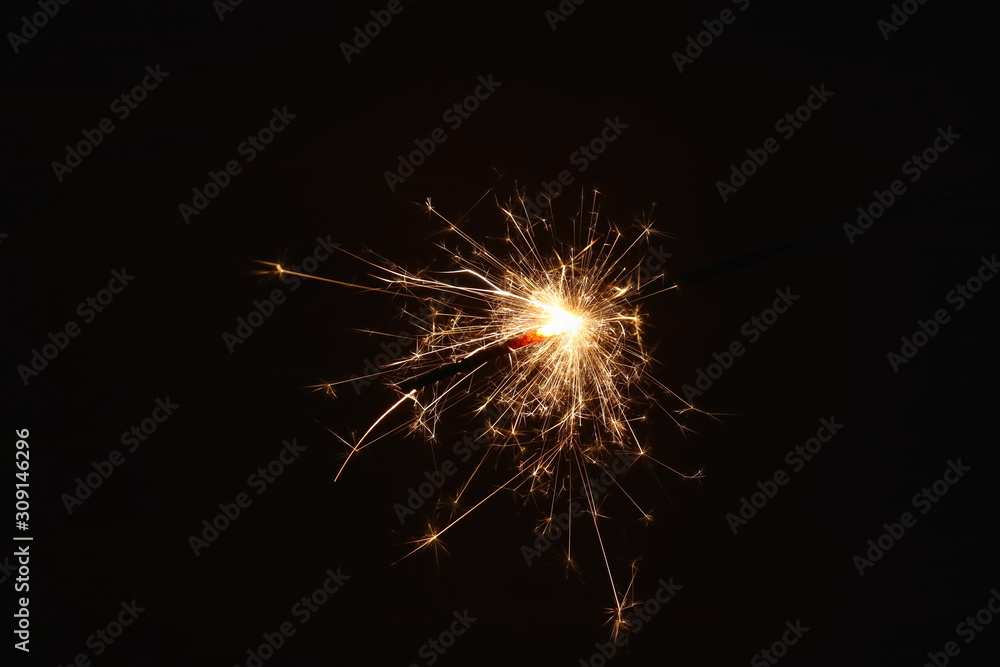 Christmas and New Year's illumination. Burning sparklers scatter bright exploding strips of sparks on a dark background.