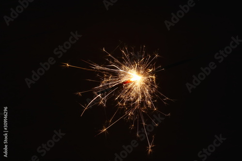 Christmas and New Year s illumination. Burning sparklers scatter bright exploding strips of sparks on a dark background.