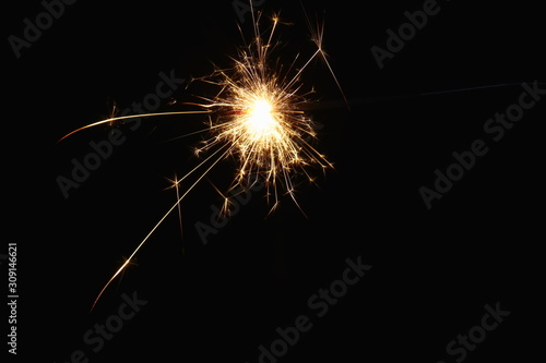 Christmas and New Year s illumination. Burning sparklers scatter bright exploding strips of sparks on a dark background.