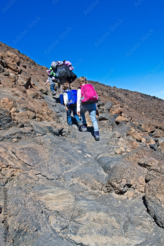 happy family makes a climb to the Teide volcano on the island of Tenerife on a stone surface natural landscape, background