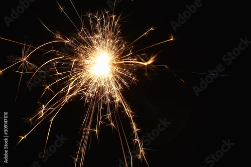 Christmas and New Year s illumination. Burning sparklers scatter bright exploding strips of sparks on a dark background.