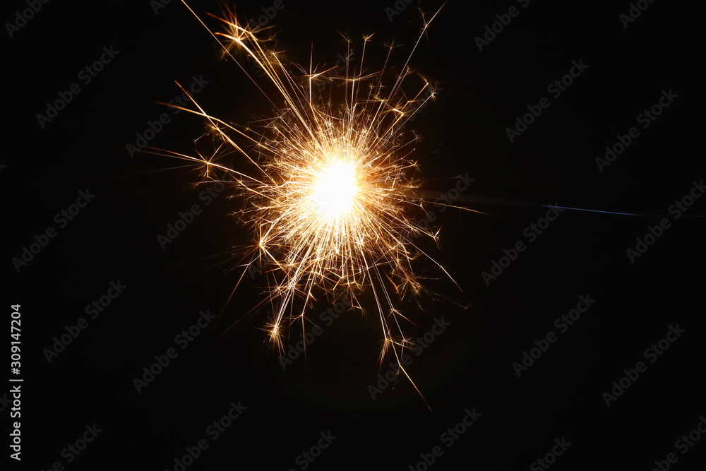 Christmas and New Year's illumination. Burning sparklers scatter bright exploding strips of sparks on a dark background.