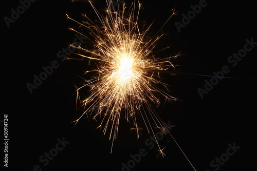 Christmas and New Year's illumination. Burning sparklers scatter bright exploding strips of sparks on a dark background.