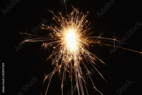 Christmas and New Year s illumination. Burning sparklers scatter bright exploding strips of sparks on a dark background.