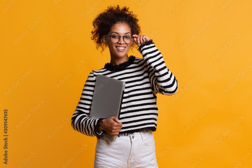 © ClaudiK - Indoor shot of beautiful happy African American student girl standing isolated in white studio smiling cheerfully