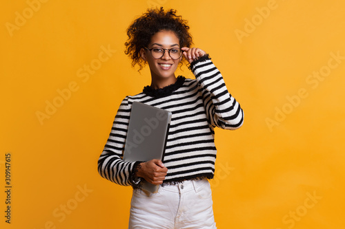 Indoor shot of beautiful happy African American student girl standing isolated in white studio smiling cheerfully