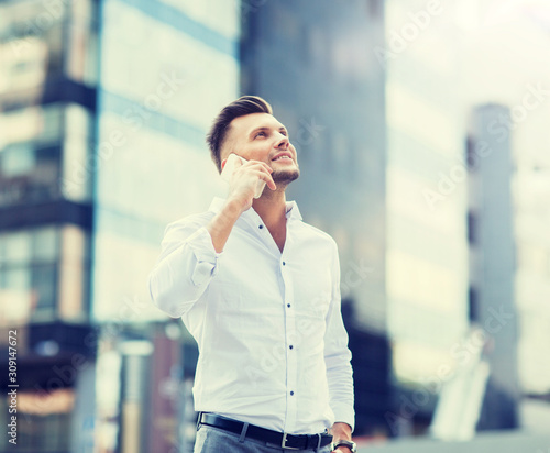 technology, communication and people concept - happy man with smartphone calling on city street