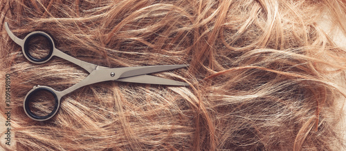 Hair close-up, background. Flat lay. Scissors, comb and background of hair with curls. The concept of haircuts, care, hair loss, baldness.