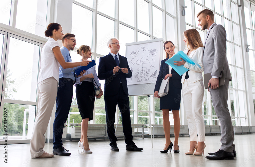 people, planning and strategy concept - business team discussing scheme on flip chart at office people, planning and strategy concept - business team discussing scheme on flip chart at office