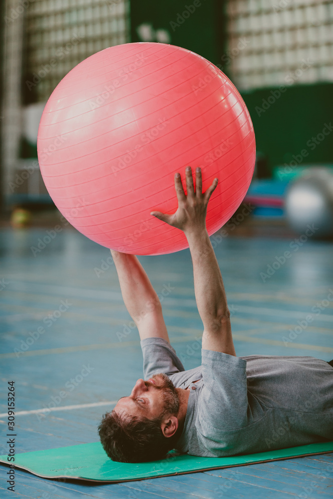 Naklejka premium Man performs exercise with big ball
