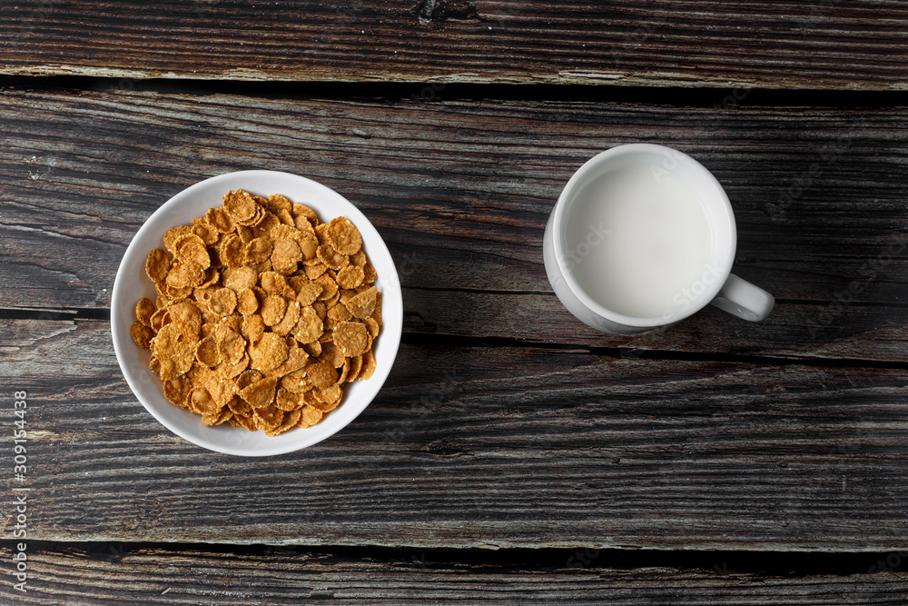 White plate with healthy cereal breakfast and cup of milk on a wooden surface. Top view. White plate with healthy cereal breakfast and cup of milk on a wooden surface. Top view.