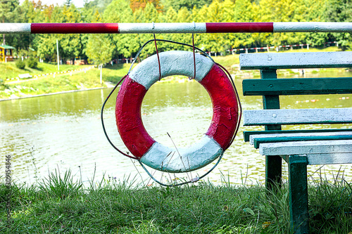 lifebuoy on the grassy shore of a reservoir, the concept of protecting and saving lives and the danger of drowning photo