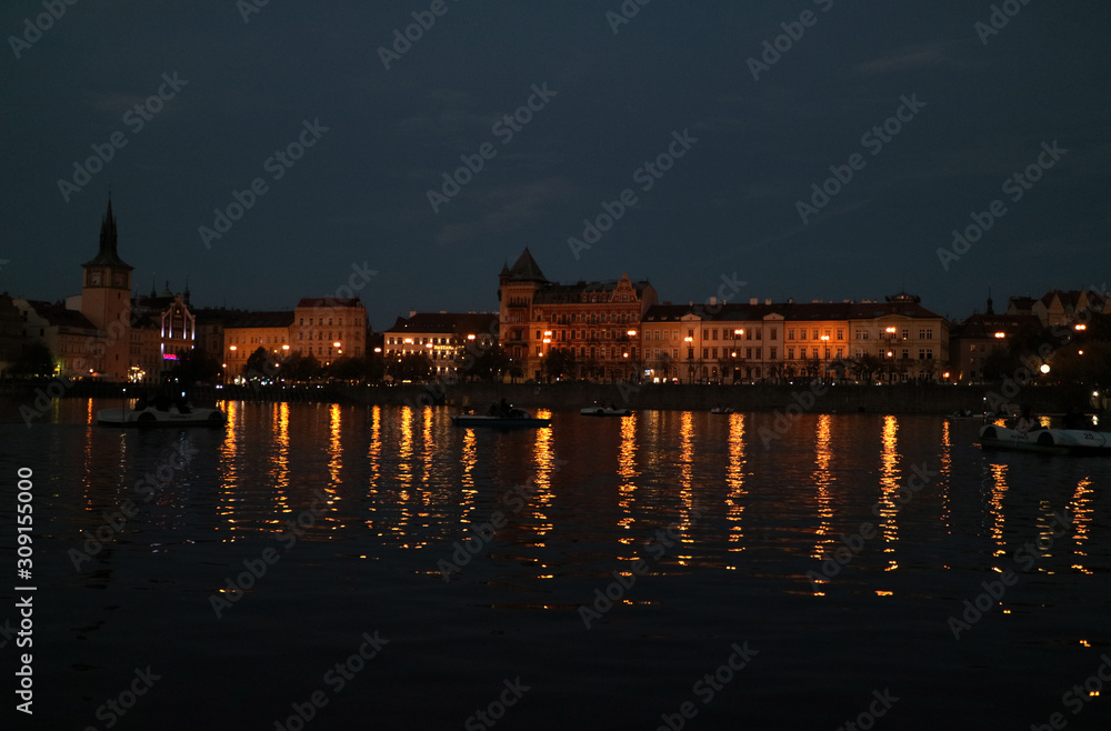 プラハのヴルタヴァ川河畔に建つ建築物の夜景と水面の反射光