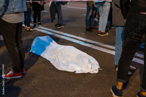 Human body covered by a sheet lying on the street.