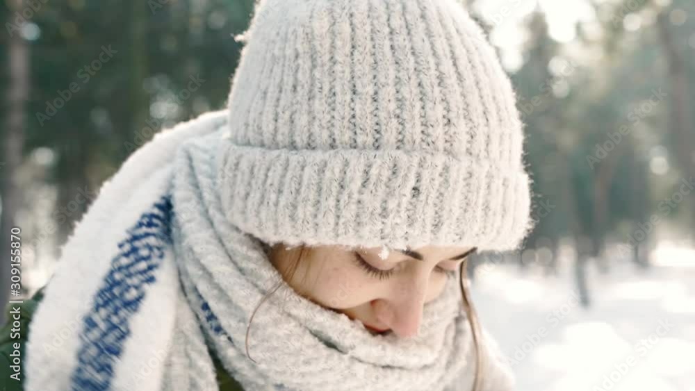 slow motion Winter portrait of funny smiling woman in woolen hat and long warm scarf in snowy winter park at frozzy sunny day. woman exhales steam and wraps herself in a scarf. Happy winter time slow motion Winter portrait of funny smiling woman in woolen hat and long warm scarf in snowy winter park at frozzy sunny day. woman exhales steam and wraps herself in a scarf. Happy winter time