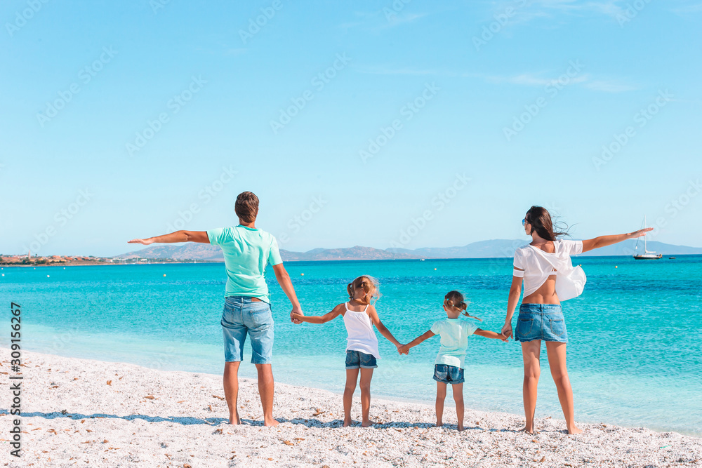 Happy beautiful family of four on white beach