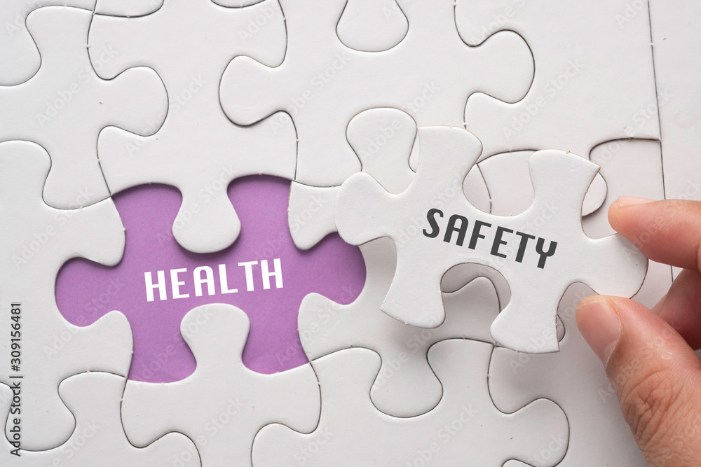 Hand hold piece of puzzle written SAFETY revealing word HEALTH. Health and Safety concept. Hand hold piece of puzzle written SAFETY revealing word HEALTH. Health and Safety concept.