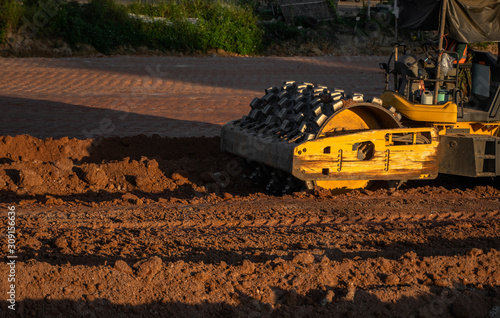 Soil compactor with vibratory padfoot drum. Heavy duty machinery working on highway construction site. Vehicle for soil compaction. Road construction equipment. Paving. Compaction of the road. photo