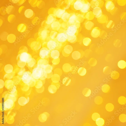 Beautiful golden Christmas light background with glowing backdrop glitter. Defocused background with gold blinking stars
