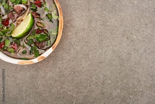 top view of pho in bowl on grey background