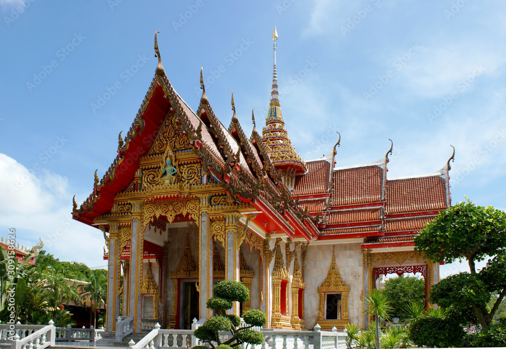 View of the traditional Asian pagoda. A white building with gold trim and a red roof against the sky. Buddhist temple facade in Thailand.