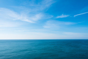 cloudy blue sky leaving for horizon above a blue surface of the sea