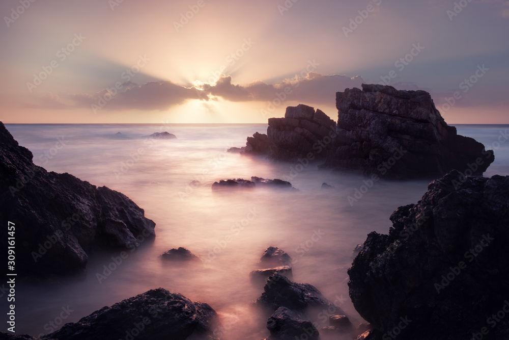 Adraga beach at amazing colors sunrise. Long exposure shot of rocky coastline, Portugal.