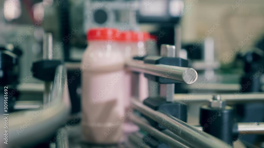 Yogurt in bottles move on a factory conveyor. Food packaging process at a food factory conveyor. Yogurt in bottles move on a factory conveyor. Food packaging process at a food factory conveyor.
