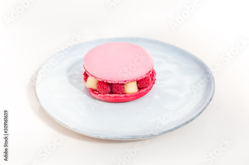 Pink macaroon with raspberry on a plate