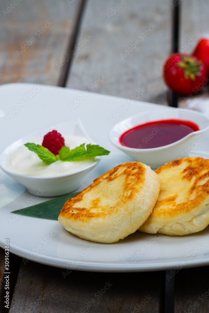 Traditional breakfast with coffee and cheesecakes, cottage cheese pancakes on a plate with syrup and jam.