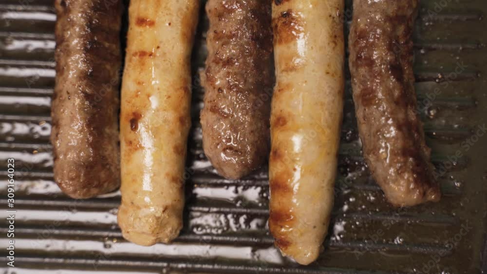 delicious grilled pork sausages rollin on hot grill pan from overhead in 4K delicious grilled pork sausages rollin on hot grill pan from overhead in 4K