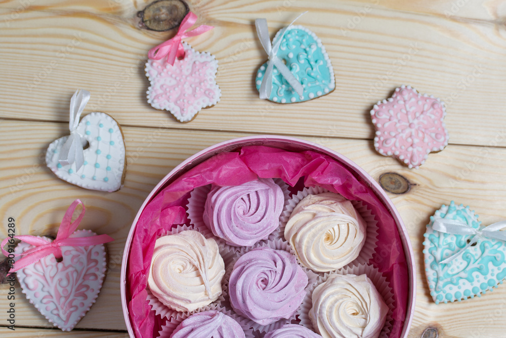 Homemade marshmallows in a round box. Spicy gingerbread cookies are laid out nearby. On pine boards. View from above. Homemade marshmallows in a round box. Spicy gingerbread cookies are laid out nearby. On pine boards. View from above.