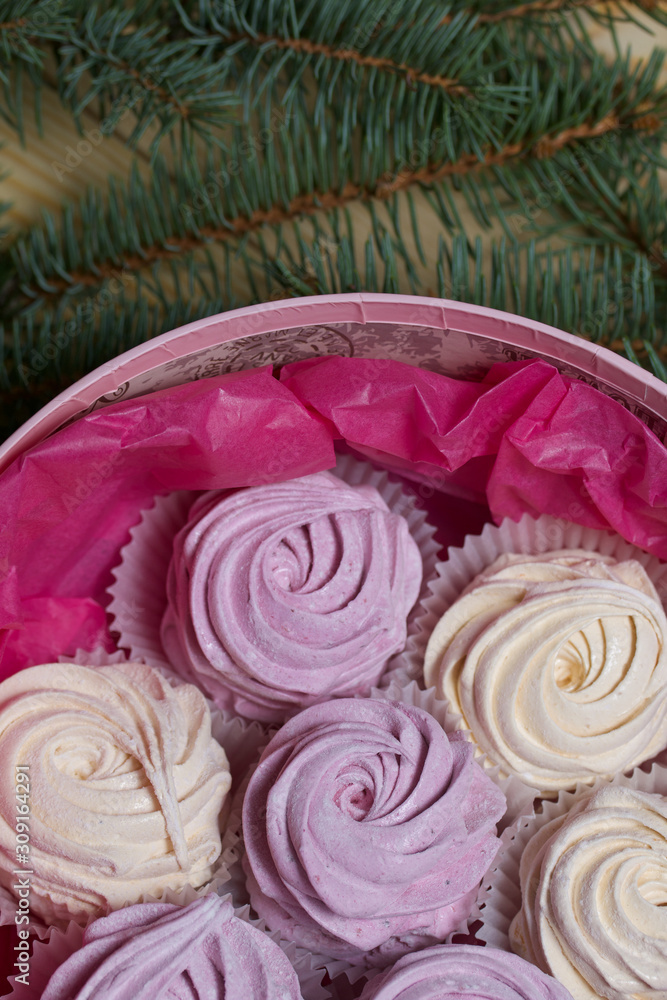 Homemade marshmallows in a round box. Decorated with fir branches. On pine boards. View from above. Homemade marshmallows in a round box. Decorated with fir branches. On pine boards. View from above.