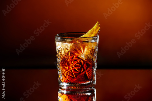A glass of whiskey with ice on an orange brown background.