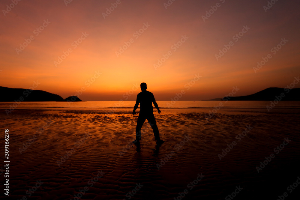 Silhouette action of a young man fun under twilight sunset sky at sea beach.
