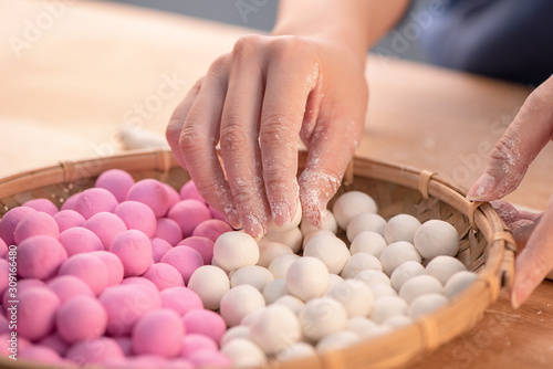 Canvas Print An Asia woman is making Tang yuan, yuan xiao, Chinese traditional food rice dumplings in red and white for lunar new year, winter festival, close up