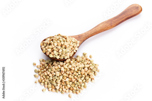 Raw buckwheat and wooden spoon on white background.