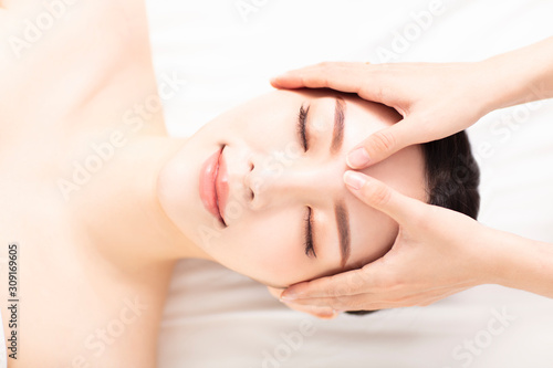 closed young woman face and head massage in spa
