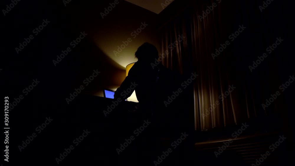 Low angle view of man sitting in front of computer in a dark room Low angle view of man sitting in front of computer in a dark room