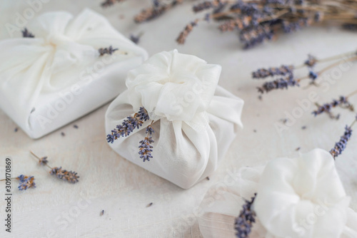 Present wrapped with white furoshiki fabric and decorated with lavender flowers. Eco friendly gift.