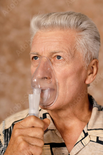 Close-up portrait of sick senior man with inhaler