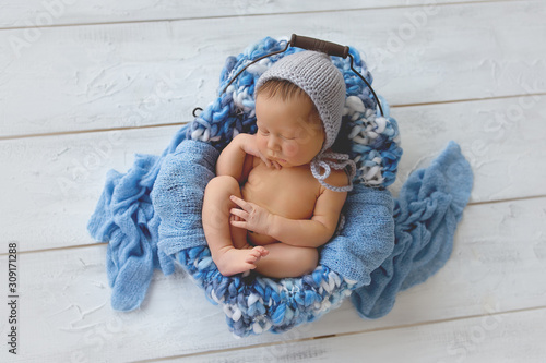 Newborn baby boy. Newborn is sleeping in a basket. Boy in blue on a white background.