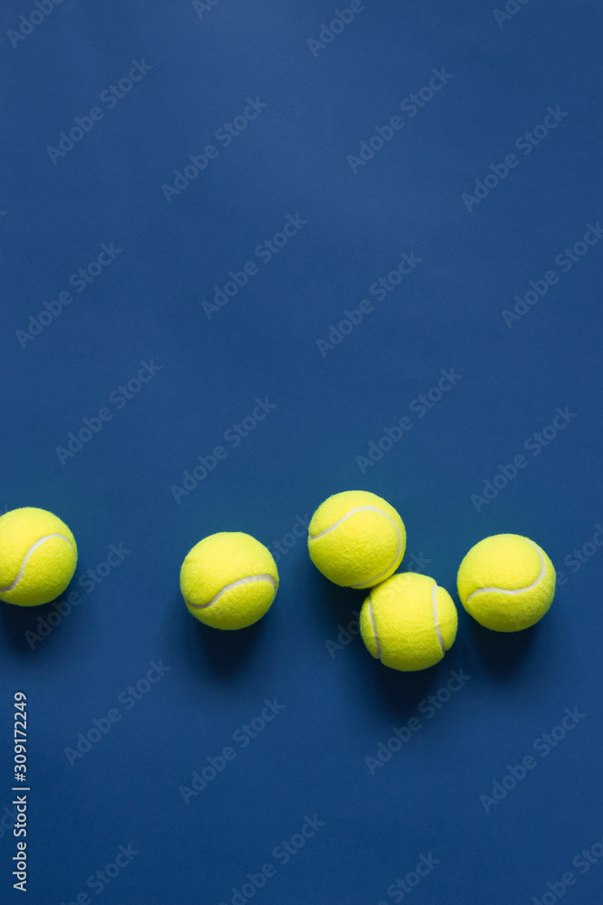 Yellow tennis balls on blue background flat lay. Color of the year 2020, vertical format photo. Active lifestyle concept. Sports equipment, above