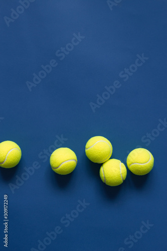 Yellow tennis balls on blue background flat lay. Color of the year 2020, vertical format photo. Active lifestyle concept. Sports equipment, above © Olha Kozachenko