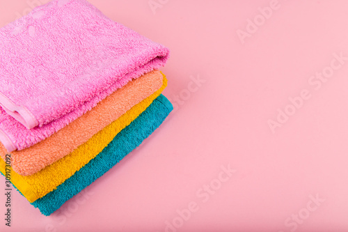 Multi-colored towels on a pink background. Pink, beige, yellow and blue flower towels. Place for writing. House order.