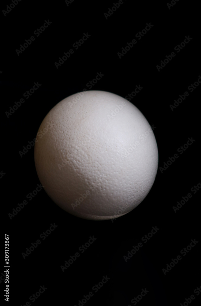 Big ostrich egg isolated on a black background, close up. Organic fresh egg. Concept of healthy food. Ostrich egg as symbol of birth. Huge white egg shell of an african ostrich. Big ostrich egg isolated on a black background, close up. Organic fresh egg. Concept of healthy food. Ostrich egg as symbol of birth. Huge white egg shell of an african ostrich.