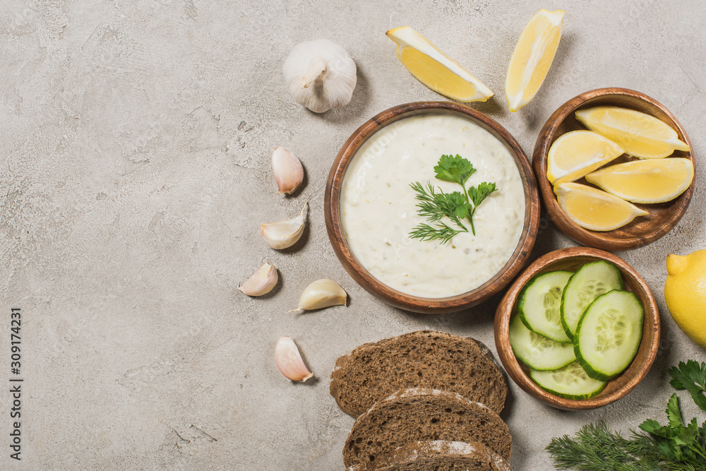 Top view of tzatziki sauce with bread and organic ingredients on stone background Top view of tzatziki sauce with bread and organic ingredients on stone background