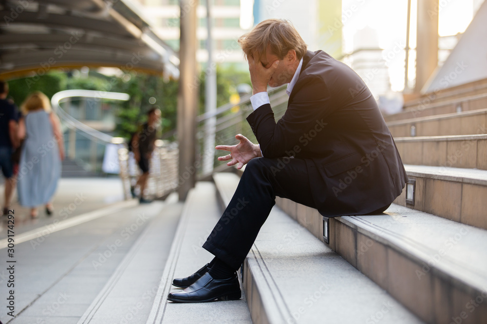 Stressed businessman in black suit sitting at stairway outdoor, Desperate for work. Stressed businessman in black suit sitting at stairway outdoor, Desperate for work.