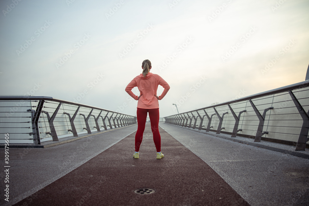 Sporty young woman standing on the bridge